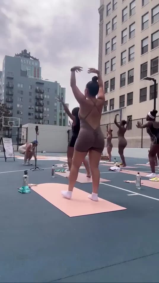 The class moving together on mats with the Downtown LA skyline behind them