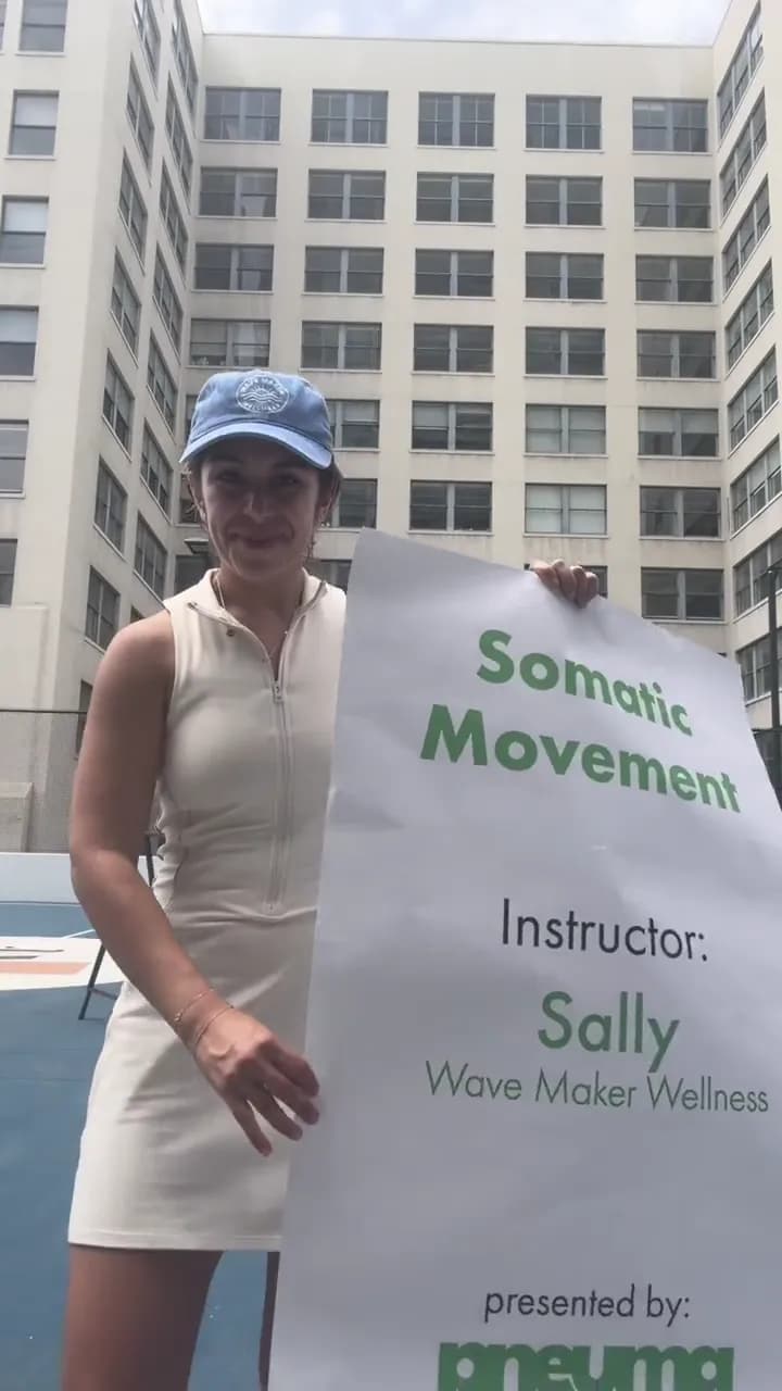 Sally holding the Somatic Movement class sign on the rooftop court
